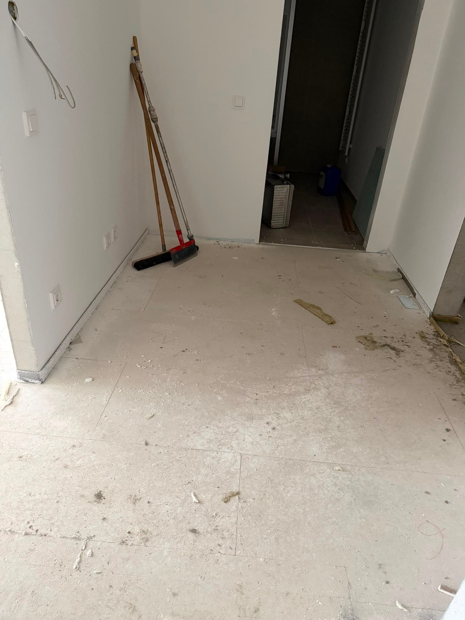 Gereinigter Untergrund mit Besen an der Wand vor Beginn der Verlegung